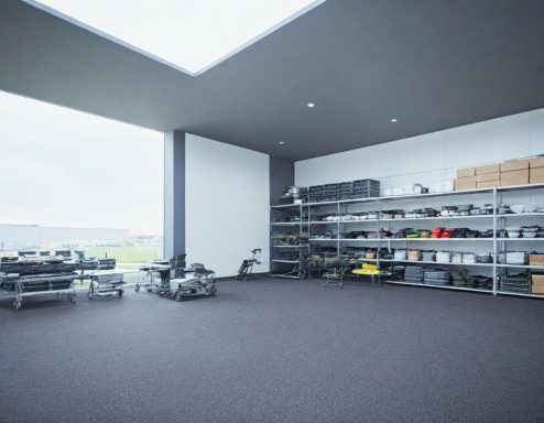 Espace de rangement moderne avec étagères, boîtes et outils, sur un sol sombre.