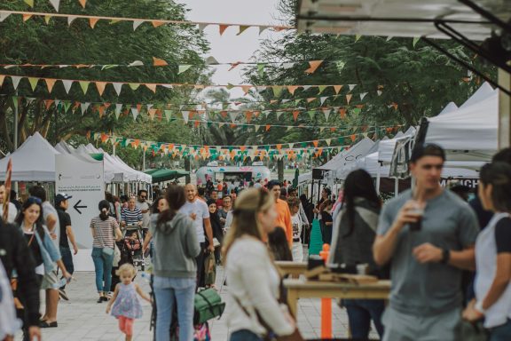 Marché animé en plein air avec des stands, des visiteurs et des décorations colorées.