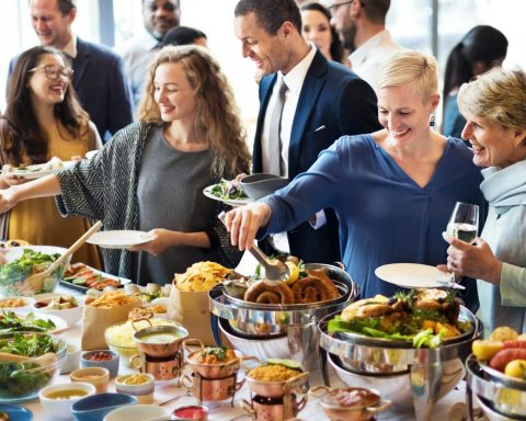 Des personnes servant des plats variés lors d'un buffet dans un cadre social.